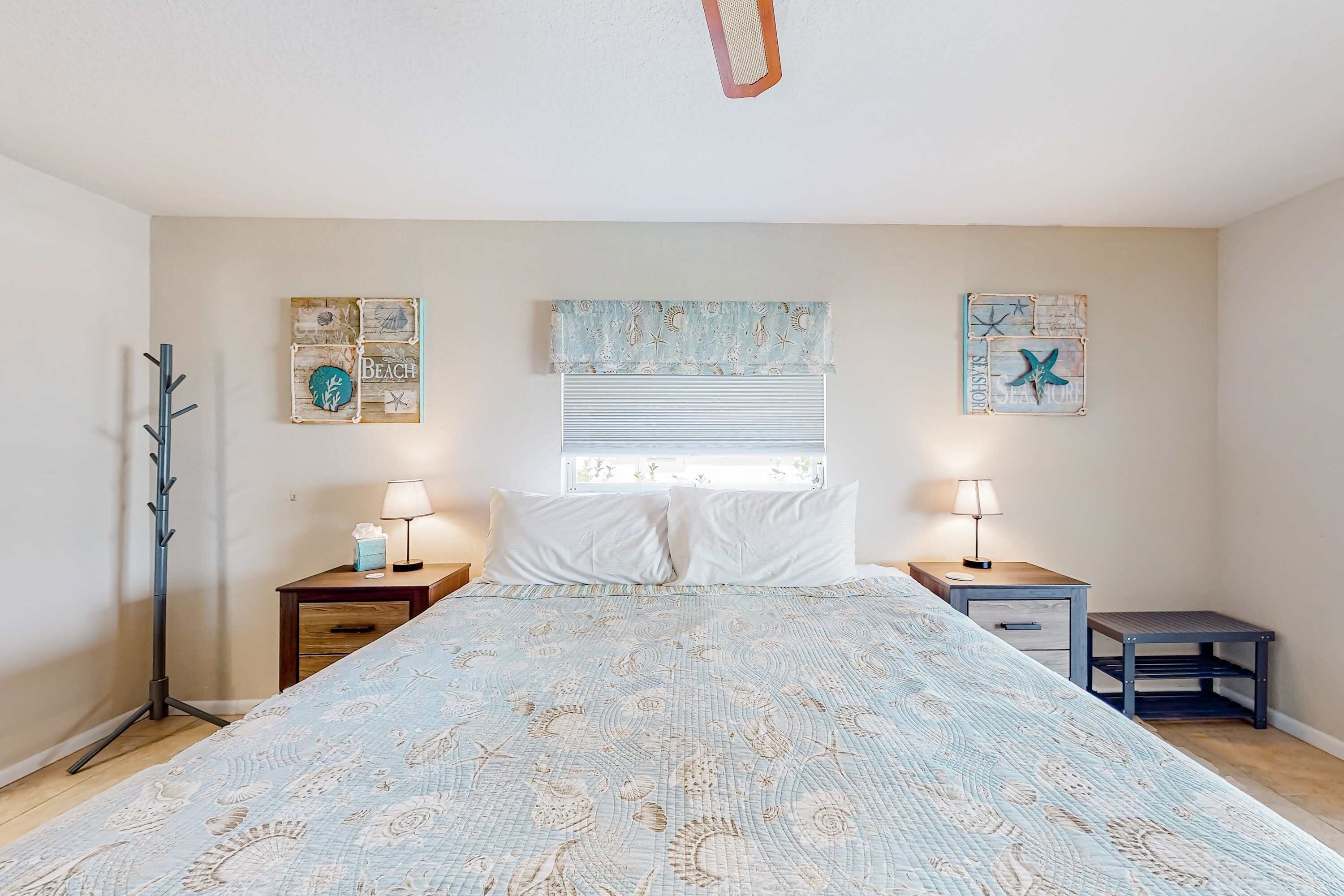 Un dormitorio con una cama, dos mesitas de noche, una lámpara de pie y decoración en la pared.