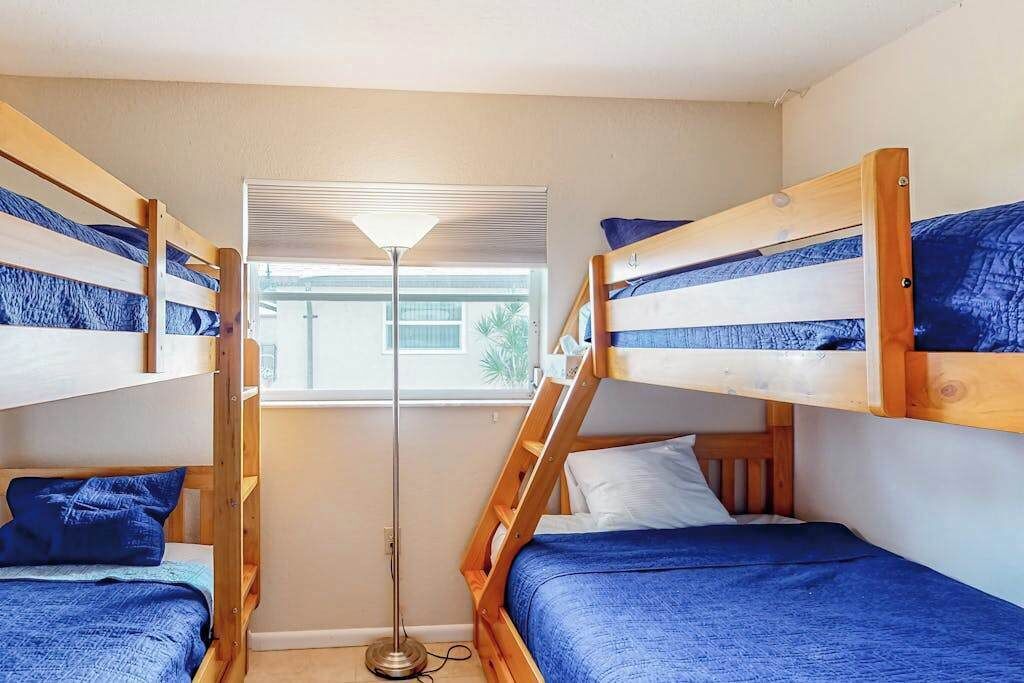 Ein Zimmer mit Etagenbetten, einer Stehlampe und einem Fenster mit Jalousien.
