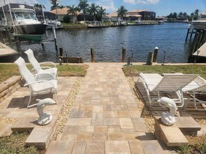 Eine Uferterrasse mit Liegestühlen, einer Delfinstatue und Blick auf den Yachthafen.