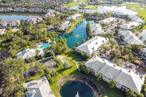 An aerial view of a residential area with houses, a golf course, and a central water feature. - Water view condo w/ access to community amenities, wifi, & outdoor private patio (Naples)