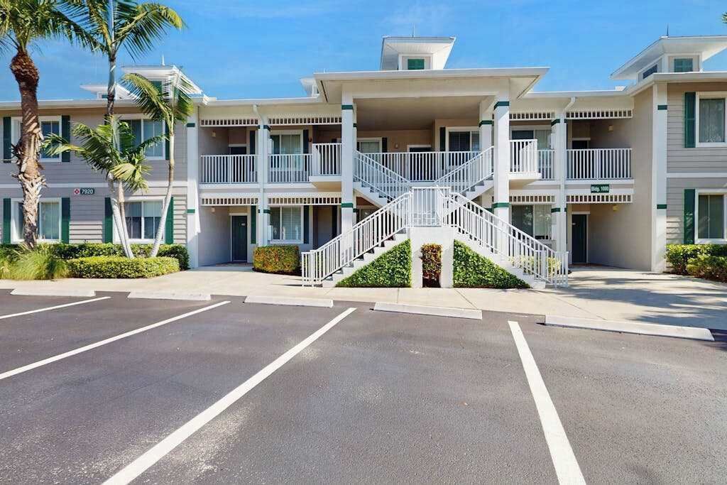 A multi-story hotel with balconies, a central staircase, and a parking lot.
