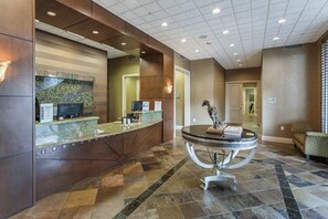 A reception area with a marble counter, a round table with a book, and a wall-mounted sculpture. - Water view condo w/ access to community amenities, wifi, & outdoor private patio (Naples)