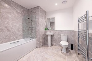A modern bathroom with a bathtub, toilet, and sink.