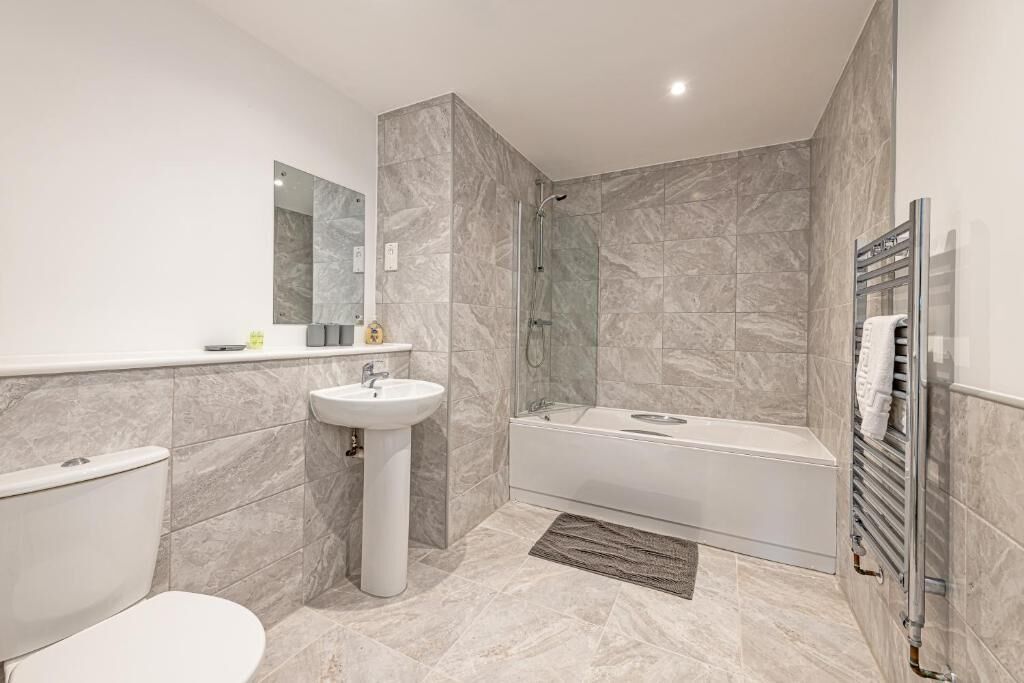 A modern bathroom with a toilet, pedestal sink, shower, and bathtub.