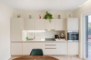 Eine moderne Küche mit Marmorfliesenspiegel, Edelstahlgeräten und einem Essbereich mit Holztisch und einem Stuhl.