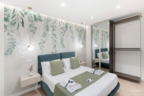 Ein modernes Hotelzimmer mit einem großen Bett, einem Nachttisch mit Blumenvase, einem Beistelltisch, einem Spiegel und einem Kleiderschrank.