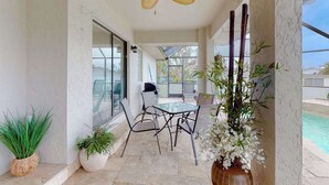 A covered patio with a ceiling fan, outdoor seating, potted plants, and a view of a swimming pool. - Canal-Front w/Private Pool & Dock – Your Florida Escape Starts Here (Punta Gorda)