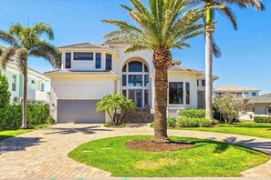 A two-story house with a garage, a driveway, and a well-maintained lawn with palm trees. - Exquisite waterfront home with lanai, heated pool and spa(hot tub), and internet (Naples)