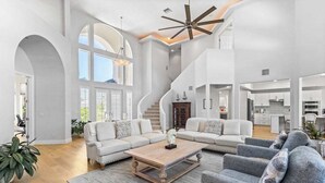 A spacious living area with a large sofa set, a coffee table, and a staircase leading to a kitchen. - Exquisite waterfront home with lanai, heated pool and spa(hot tub), and internet (Naples)