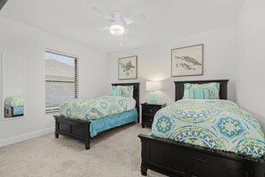 A bedroom with two beds, a ceiling fan, and artwork on the walls. - Dog-Friendly Waterfront Escape with Heated Pool & Outdoor Grill (Cape Coral)