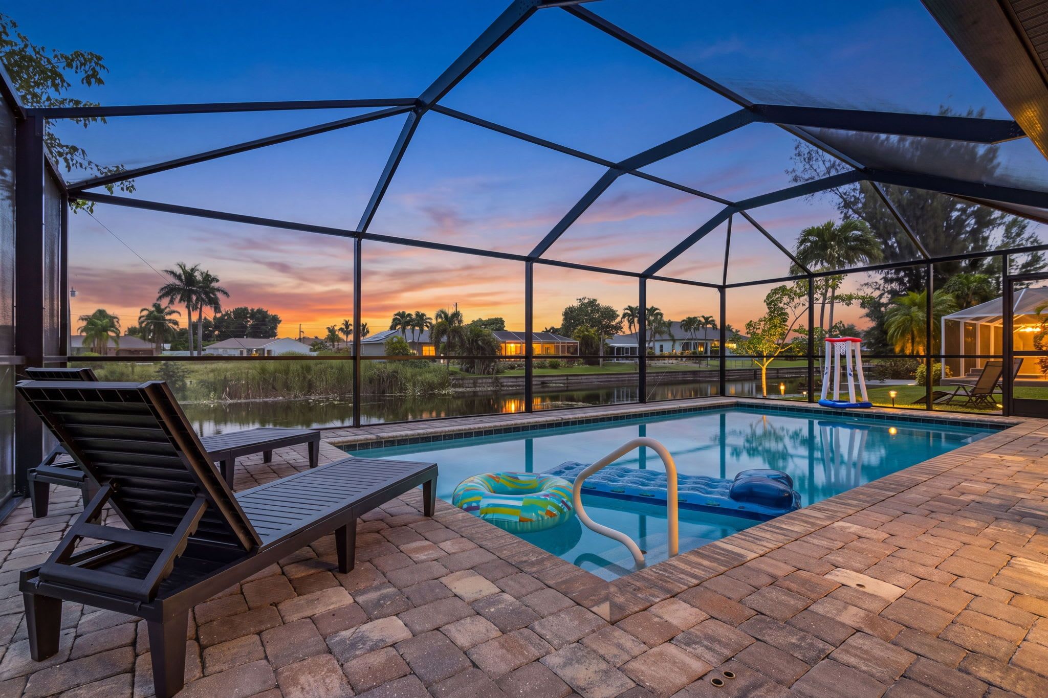 Una piscina con zona cubierta, sillas de descanso y vistas al atardecer.