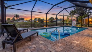 Una piscina con zona coperta, lettini e vista sul tramonto.