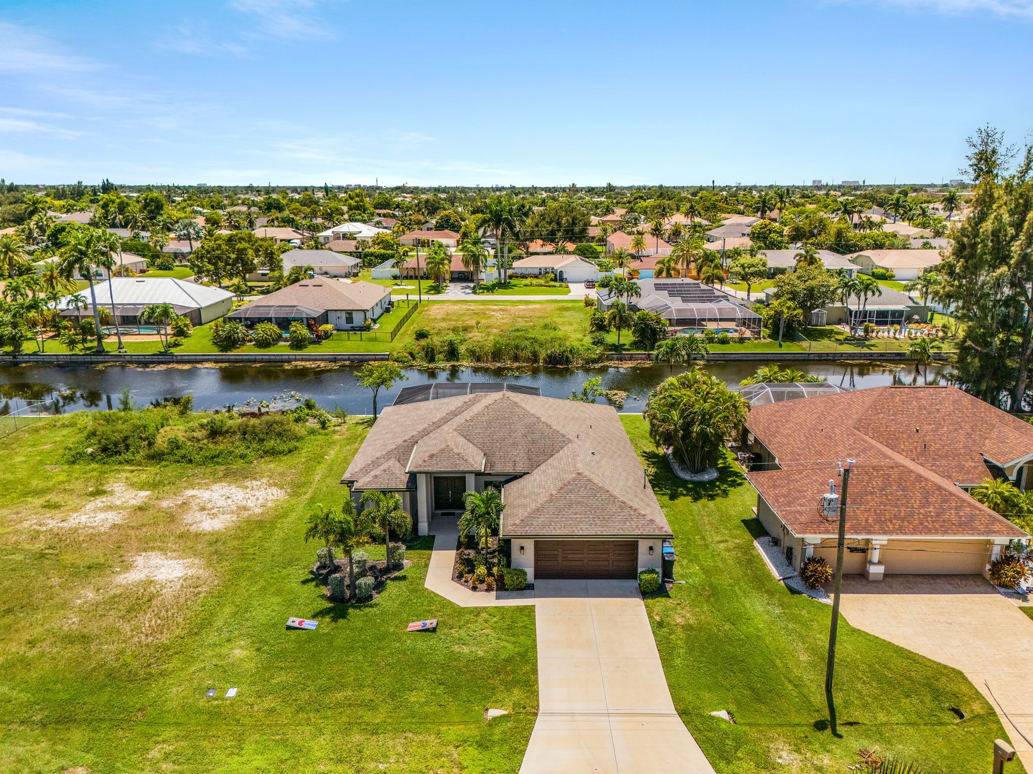 A residential area with houses, a body of water, and a well-maintained lawn.