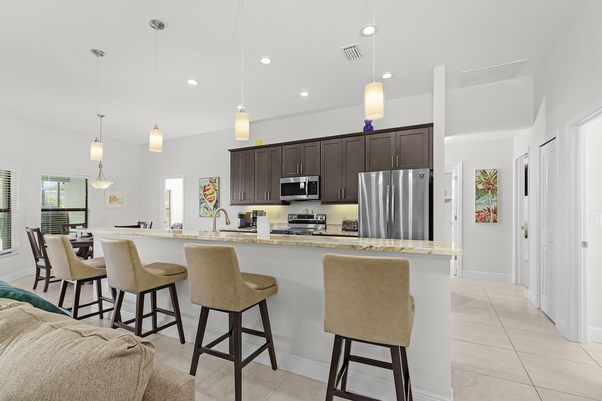 A modern kitchen with dark cabinets, stainless steel appliances, and pendant lighting.