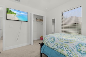 A bedroom with a bed, a television on the wall, a closet, and a window with blinds. - Dog-Friendly Waterfront Escape with Heated Pool & Outdoor Grill (Cape Coral)