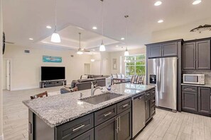 A modern kitchen with granite countertops, stainless steel appliances, and dark cabinetry. - Delightful home near beaches with heated pool, patio, lanai, grill, & streaming (Bonita Springs)