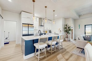 A modern kitchen with a central island, bar stools, pendant lighting, and a view to the living area. - Placida at Meadows & Villas; brand-new duplex, dogs OK, golf courses nearby (Placida)