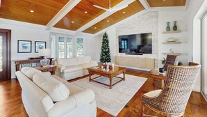 A spacious living room with a large TV, wooden ceiling, and a Christmas tree. - Spacious canal front home with private pool, dock & close to everything (Marco Island)