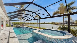 A swimming pool with a mosaic edge, a covered patio area, and a view of a lake. - Spacious canal front home with private pool, dock & close to everything (Marco Island)