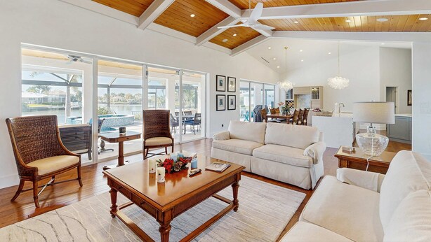 A spacious living area with a high ceiling, wooden beams, and large windows. - Spacious canal front home with private pool, dock & close to everything (Marco Island)