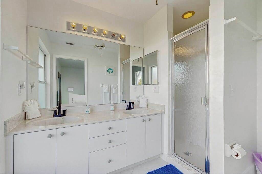 Un baño moderno con dos lavamanos, un espejo grande y una cabina de ducha.