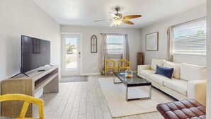 A living room with a TV, sofa, coffee table, and chairs. - Cozy coastal duplex with full kitchen, close to beach & shopping (Naples)