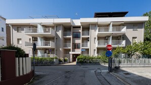 A multi-story residential building with balconies, a stop sign, and a gated entrance. - GuestHost - Alba Cozy Flat near the Sea W/Parking (Alba Adriatica)