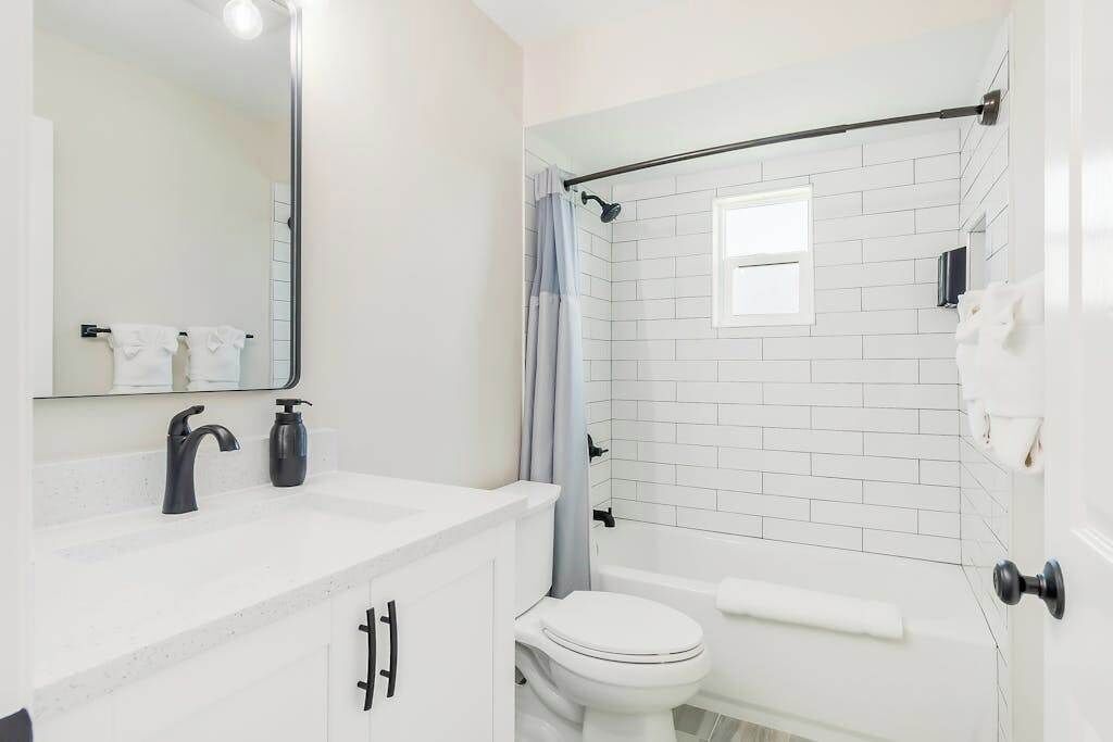 Une salle de bain moderne avec un lavabo blanc, un robinet noir et des toilettes blanches.
