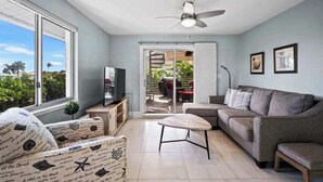 A living room with a sofa, a coffee table, a TV, and a ceiling fan. - Dog-friendly duplex with a patio, deck, washers, dryers, & central AC (Naples)