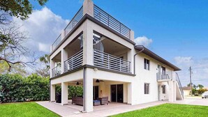 A two-story house with a balcony, a covered patio, and a garage. - Dog-friendly duplex with a patio, deck, washers, dryers, & central AC (Naples)
