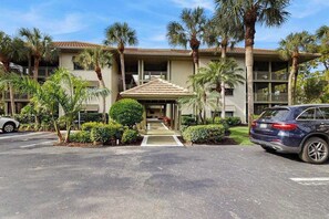 A hotel with a covered entrance, palm trees, and a parking area. - Quaint condo w/private patio, wifi, & access to community amenities (Bonita Springs)