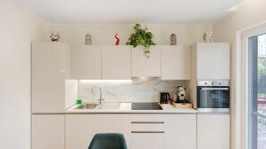 Une cuisine moderne avec un revêtement mural en marbre, des appareils en acier inoxydable et un coin repas comprenant une table en bois et une seule chaise.