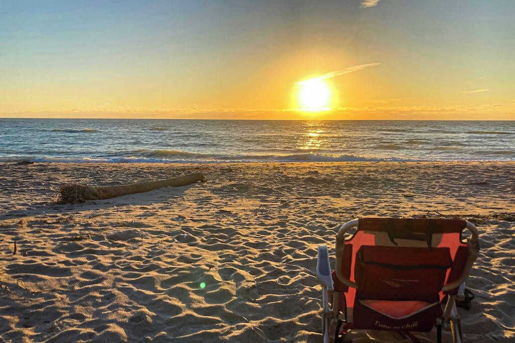 Een strand met een stoel en een boomstam.