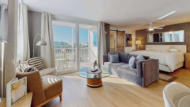 Una habitación de hotel con balcón, una cama, un sofá, una mesita de café y un escritorio.