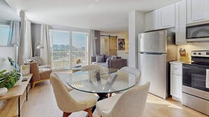 Una cocina moderna con una mesa de comedor de vidrio, armarios blancos y electrodomésticos de acero inoxidable.