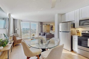 A modern kitchen with a glass dining table, white cabinets, and stainless steel appliances. - Gorgeous condo with modern upgrades, Gulfviews & shared pool (Bonita Springs)
