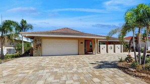 A residential house with a tiled roof, a garage, and a paved driveway. - Snowbird Retreat – Canal Home w/Pool, Game Room & Pet Friendly (Punta Gorda)