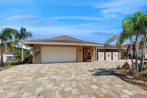 A residential house with a tiled roof, a garage, and a paved driveway. - Snowbird Retreat – Canal Home w/Pool, Game Room & Pet Friendly (Punta Gorda)