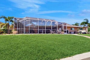 A house with a large glass-enclosed patio area. - Snowbird Retreat – Canal Home w/Pool, Game Room & Pet Friendly (Punta Gorda)
