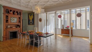 A dining area with a wooden cabinet, a stained glass window, and a view through large windows. - Paris Opera Prestige residence (Paris)