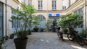 A courtyard with potted plants, a bicycle, and a building with a blue sign. - Paris Opera Prestige residence (Paris)