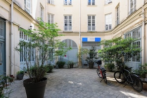 Ein Innenhof mit Blumentöpfen, einem Fahrrad und einem Gebäude mit einer blauen Schilderung.