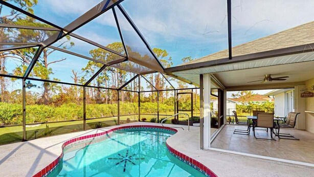 Une piscine entourée de parois en verre, un espace patio aménagé avec du mobilier d’extérieur et une vue sur le paysage environnant.