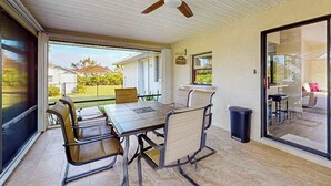 Un espace de vie à aire ouverte comprenant une table à manger, des chaises, un ventilateur de plafond et une porte-fenêtre coulissante donnant sur un patio.