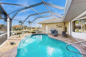A swimming pool with a glass ceiling, a patio area, and a view of the surrounding neighborhood.