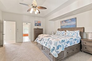 Una camera da letto con un letto grande, una ventola a soffitto, un comò e un quadro appeso al muro.