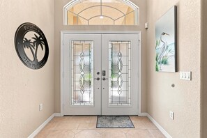 A double door with glass panels and a palm tree logo on the wall to the left.