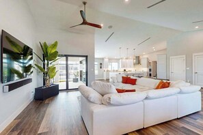 Ein modernes Wohnzimmer mit einem weißen Sofa, einem Deckenventilator und einer großen Pflanze.