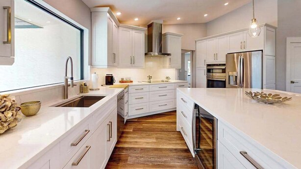 A modern kitchen with white cabinetry, stainless steel appliances, and a wooden floor. - Dazzling coastal home with private pool & spa, lanai, AC, W/D, WiFi (Marco Island)