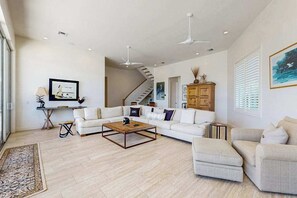 A spacious living room with a large white sofa, a coffee table, and a staircase leading to another level. - Dog-friendly waterfront getaway with lanai, private pool, & pool spa (Marco Island)